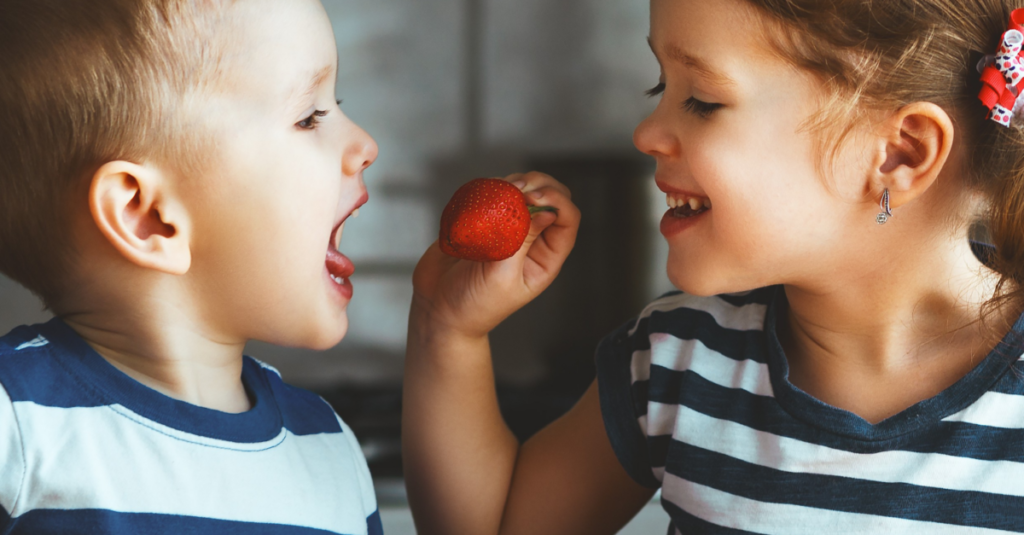 Two kids eating strawberries 1200x627
