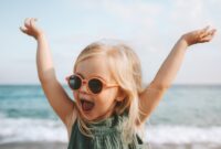 Funny kid girl playing outdoor surprised emotional child in sunglasses 3 years old baby raised hands