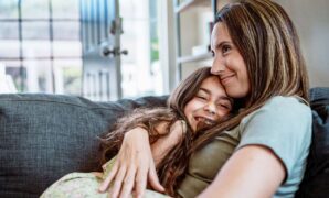 Young girl and mother hug each other on the couch 1891412676 1258x838.jpeg