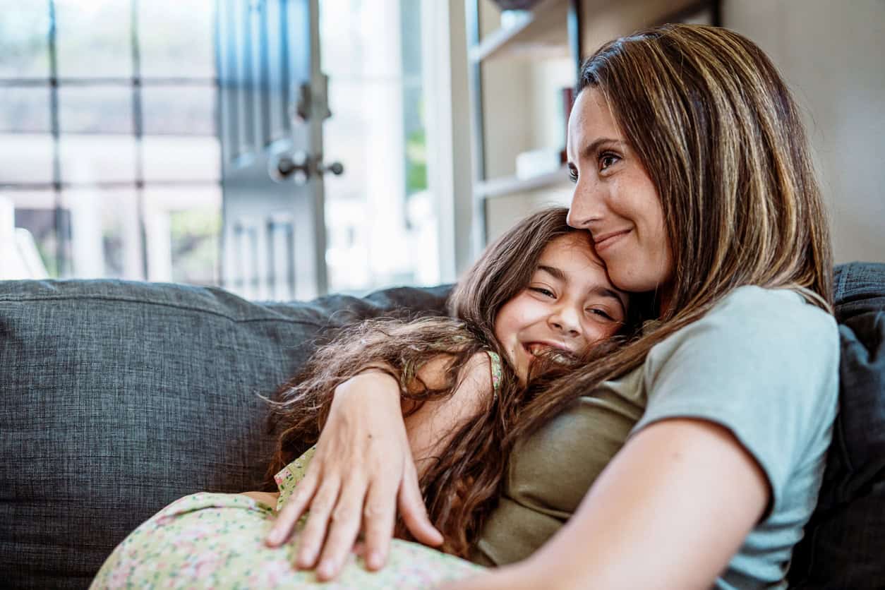 Young girl and mother hug each other on the couch 1891412676 1258x838.jpeg