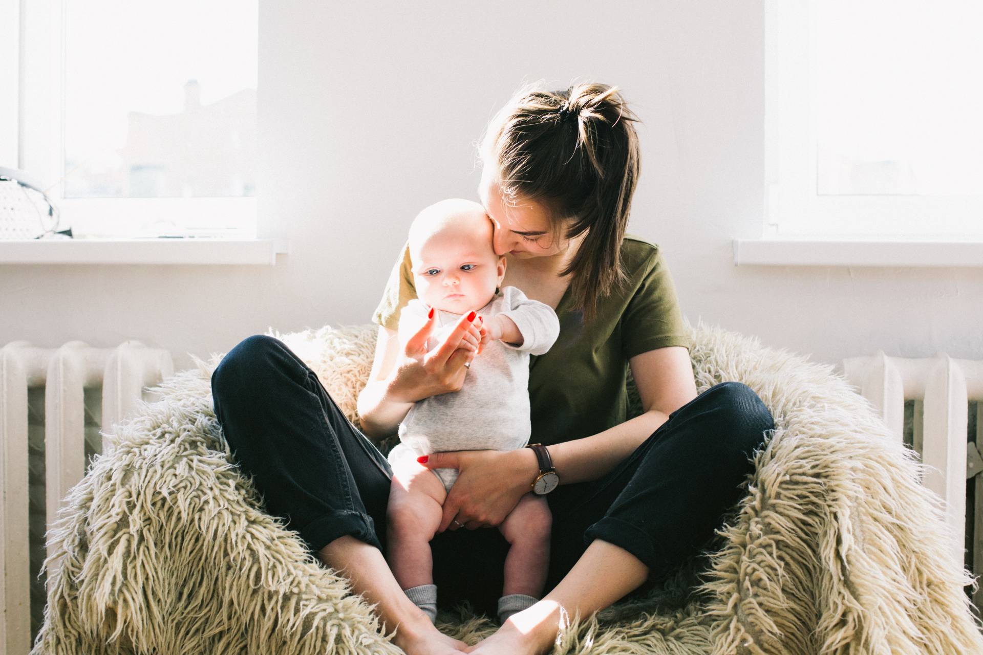 woman holding baby while sitting on fur bean bag 698878.jpg