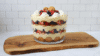 NanoBanana Side view of completed vanilla pudding trifle in clear glass bowl showing distinct layers.png