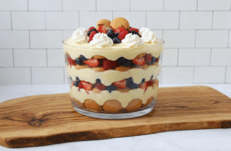 NanoBanana Side view of completed vanilla pudding trifle in clear glass bowl showing distinct layers.png